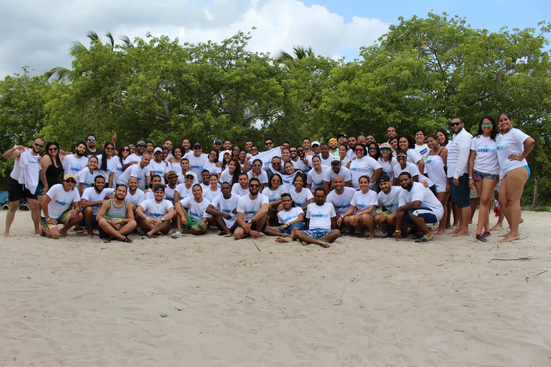 Colaboradores de Teleperformance con camisetas SUPERDAY posando en grupo en la playa de Isla Saona, República Dominicana