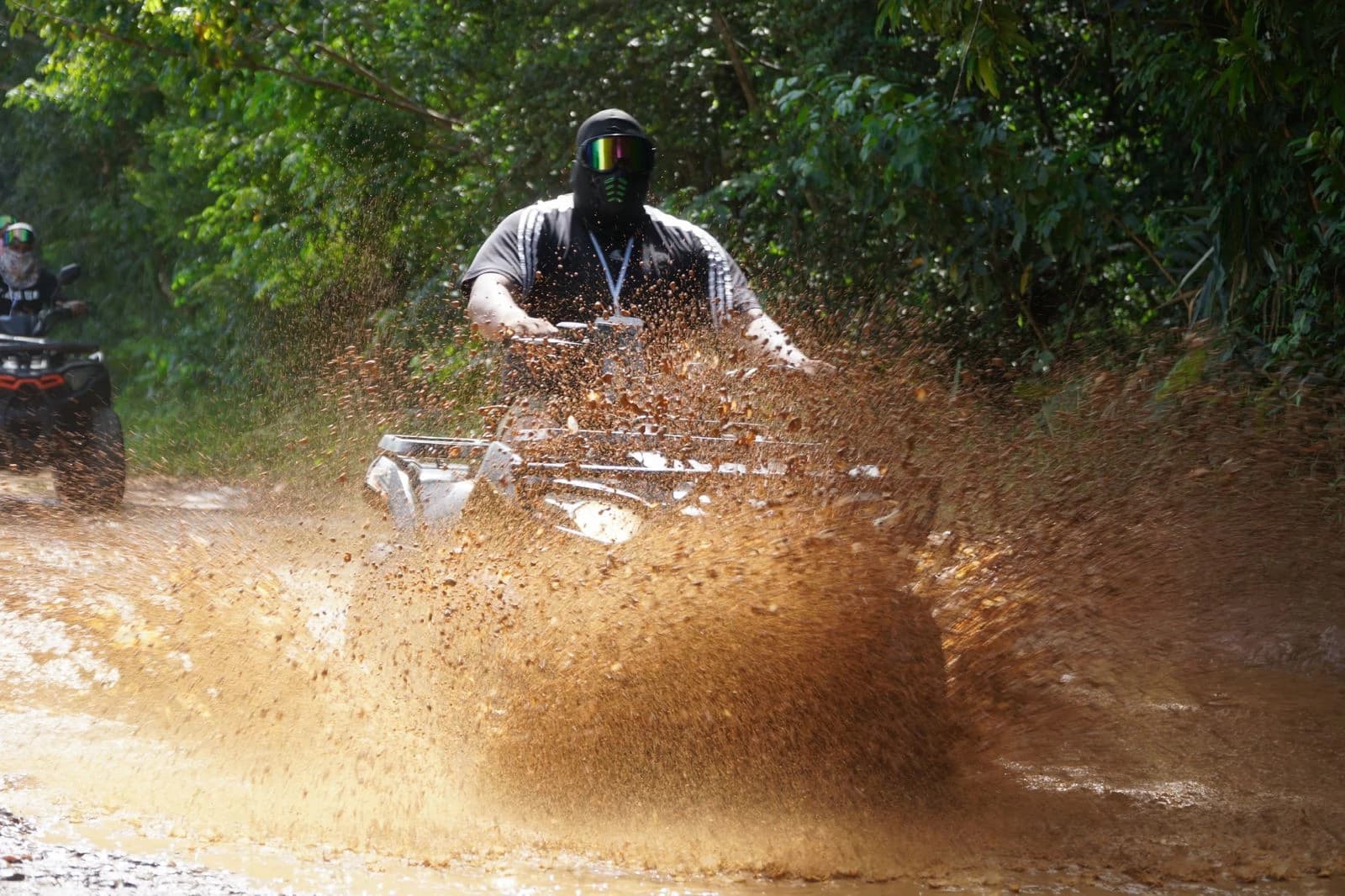 Rider on ATV splashing mud during Comatillo off-road tour in Santo Domingo.