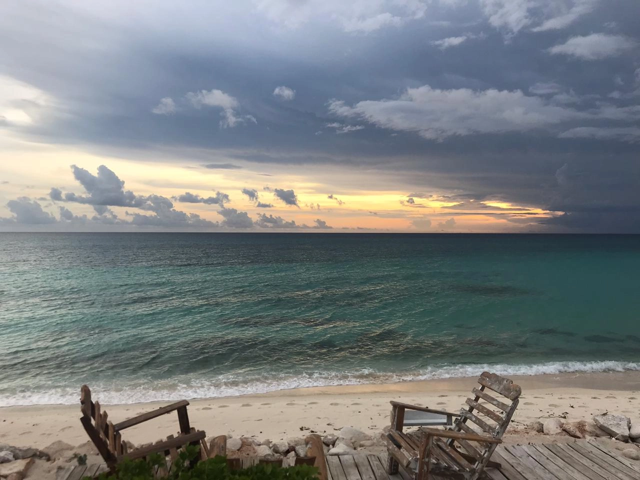 Wooden chairs facing the ocean at sunset in Cabo Rojo