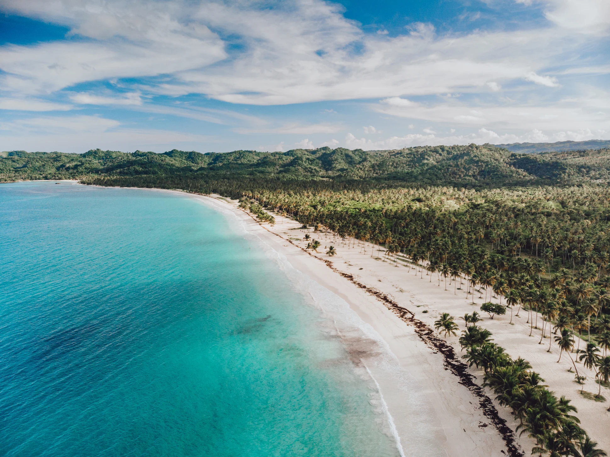 Aerial view of Playa Esmeralda with turquoise waters, white sand, and lush green forest.