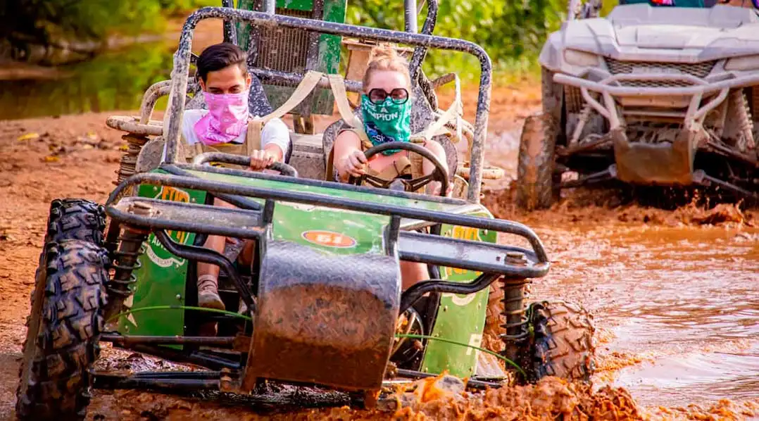 Travelers driving an ATV buggy through muddy trails in the Dominican Republic during the Full Dominican Adventure.