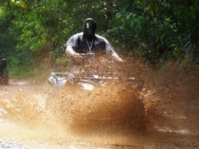 Rider on ATV splashing mud during Comatillo off-road tour in Santo Domingo.