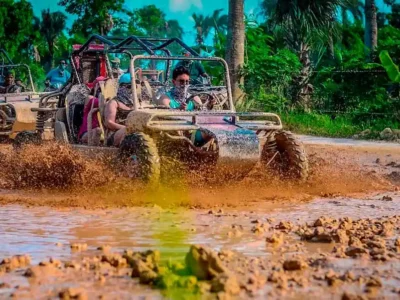 A group of travelers driving ATVs and buggies splashing through mud puddles on the Full Dominican Adventure tour.