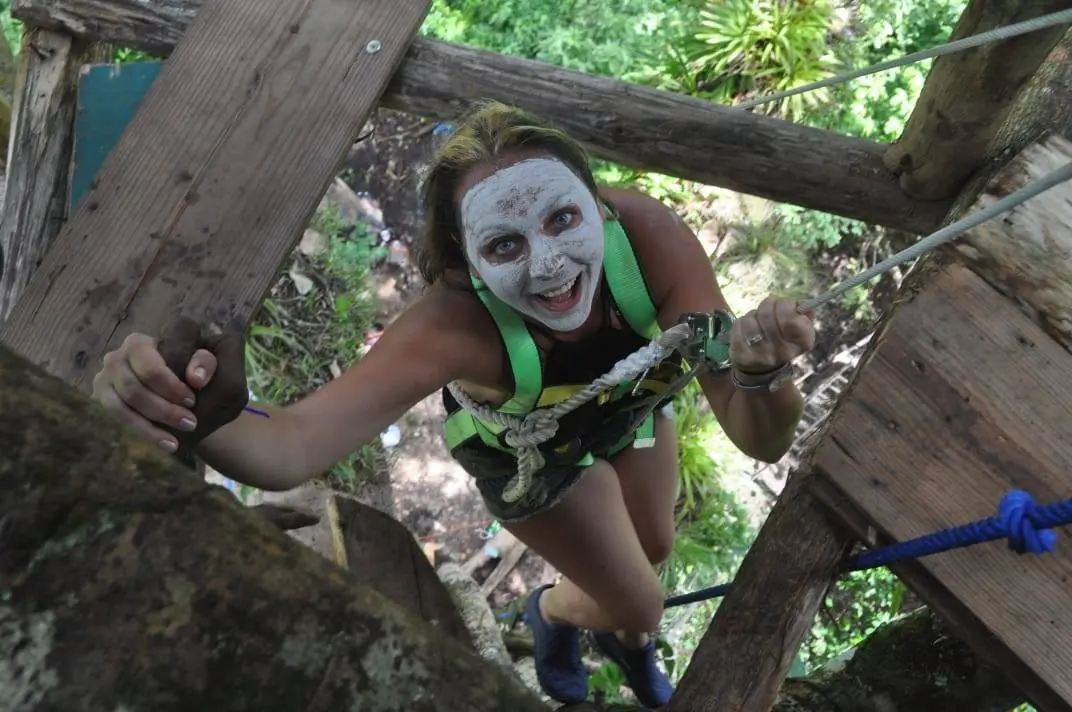 Traveler climbing Tarzan’s Treehouse with Yanigua mud mask during Amber Route tour in Hato Mayor, Dominican Republic