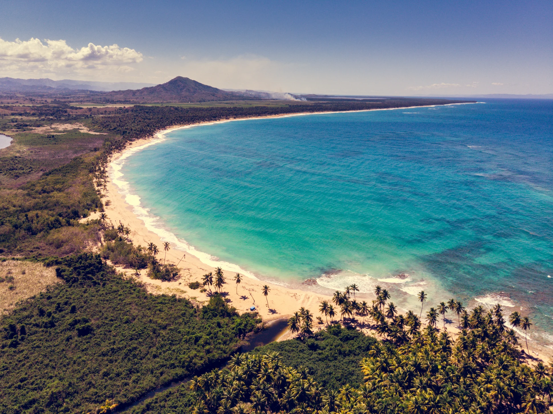 Wide aerial shot of Playa Esmeralda coastline with turquoise waters and sandy beach.