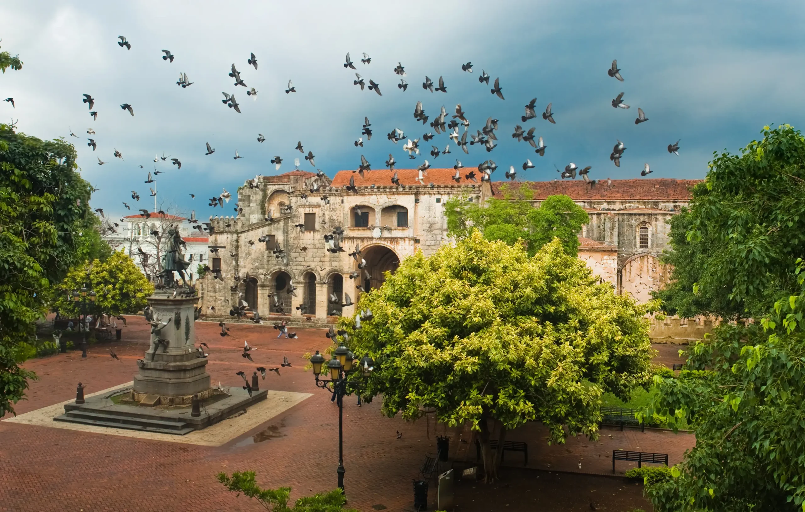 View of the Cathedral of Santa Maria la Menor and Columbus Park with flying pigeons in the Colonial Zone Santo Domingo Dominican Republic