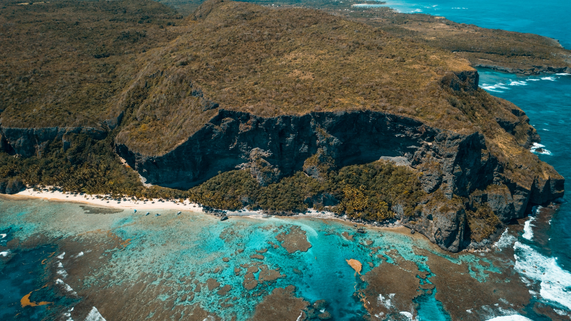 Wide panoramic drone shot of Playa Frontón’s beach and cliffs in Samaná, Dominican Republic.
