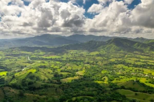 Panoramic view of green mountains and valleys in the Dominican Republic under cloudy skies.