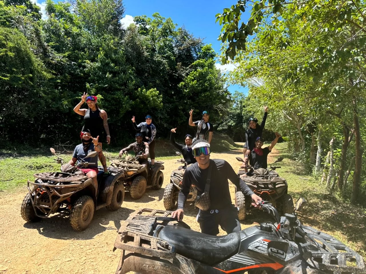 Group of travelers enjoying ATV adventure in Comatillo with muddy trails and tropical forest background