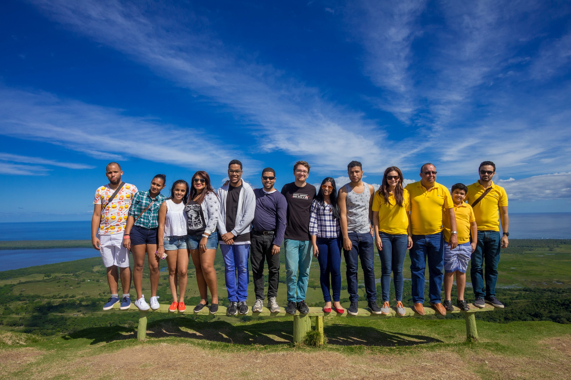 Group of friends posing together on a bench at Montaña Redonda with panoramic landscape in the background.