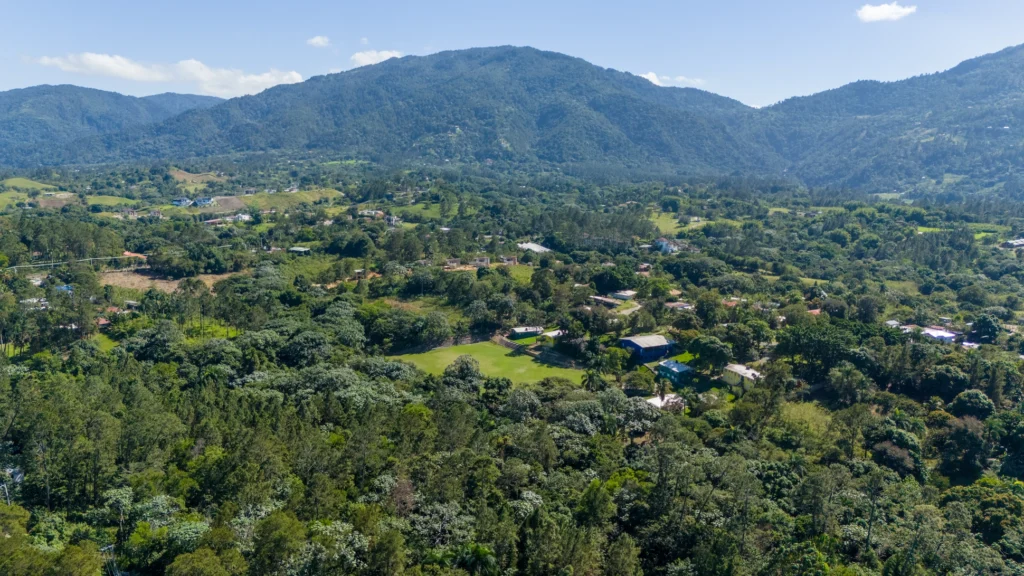 Aerial view of Jarabacoa, Dominican Republic, a mountain town surrounded by lush green valleys and pine-covered hills.