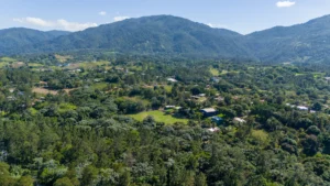 Aerial view of Jarabacoa, Dominican Republic, a mountain town surrounded by lush green valleys and pine-covered hills.