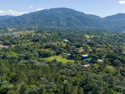 Aerial view of Jarabacoa, Dominican Republic, a mountain town surrounded by lush green valleys and pine-covered hills.