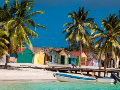 Colorful houses in Mano Juan Saona Dominican Republic with palm trees and fishing boats by the beach.