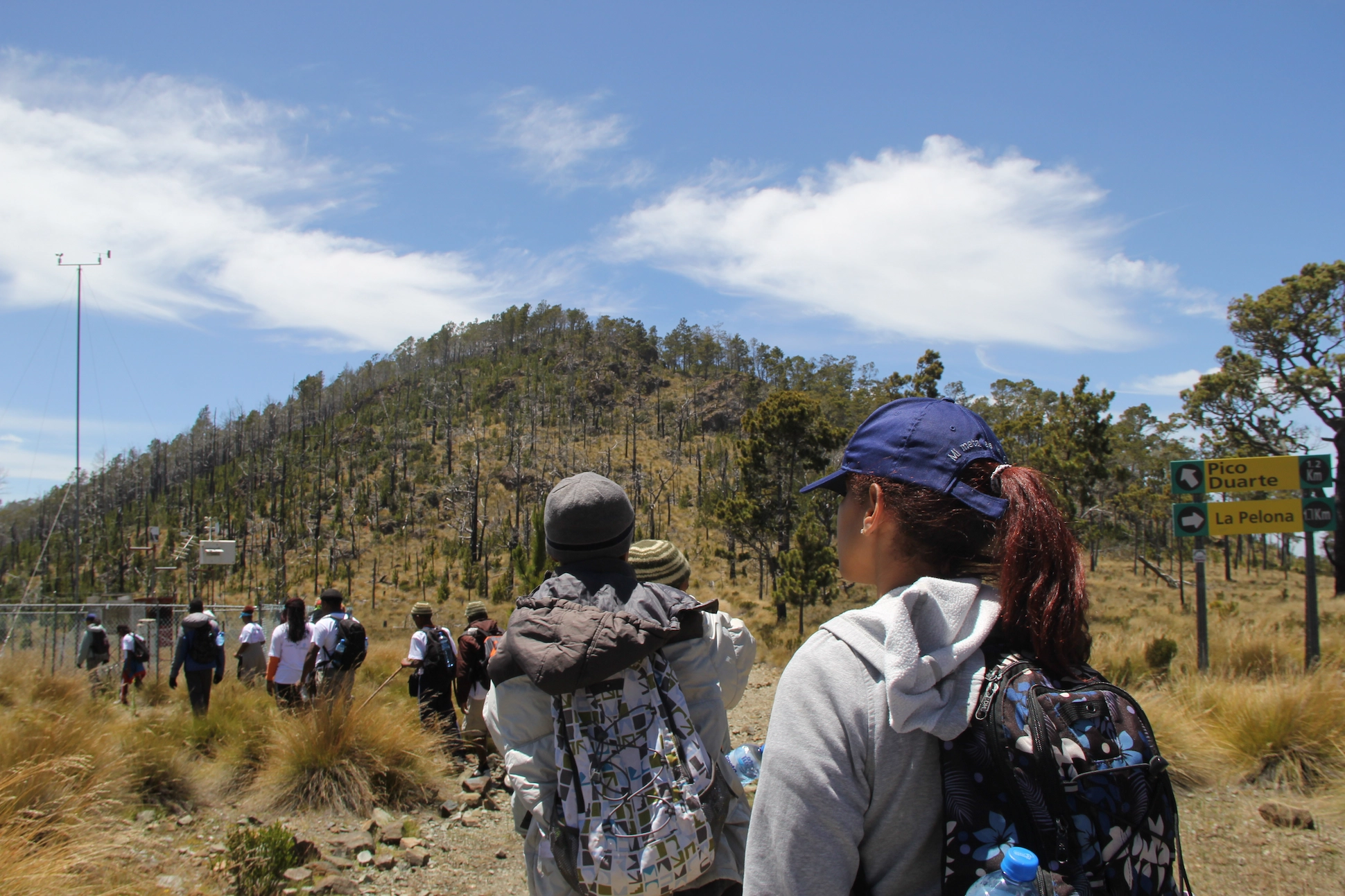 Group of hikers near Pico Duarte summit trail sign in Dominican Republic