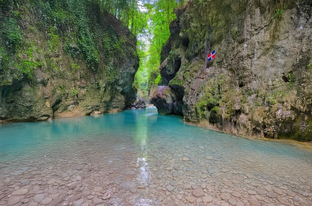 Río Partido turquoise pool with Dominican flag on the canyon wall