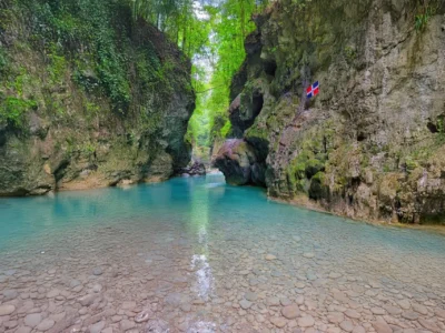Río Partido turquoise pool with Dominican flag on the canyon wall