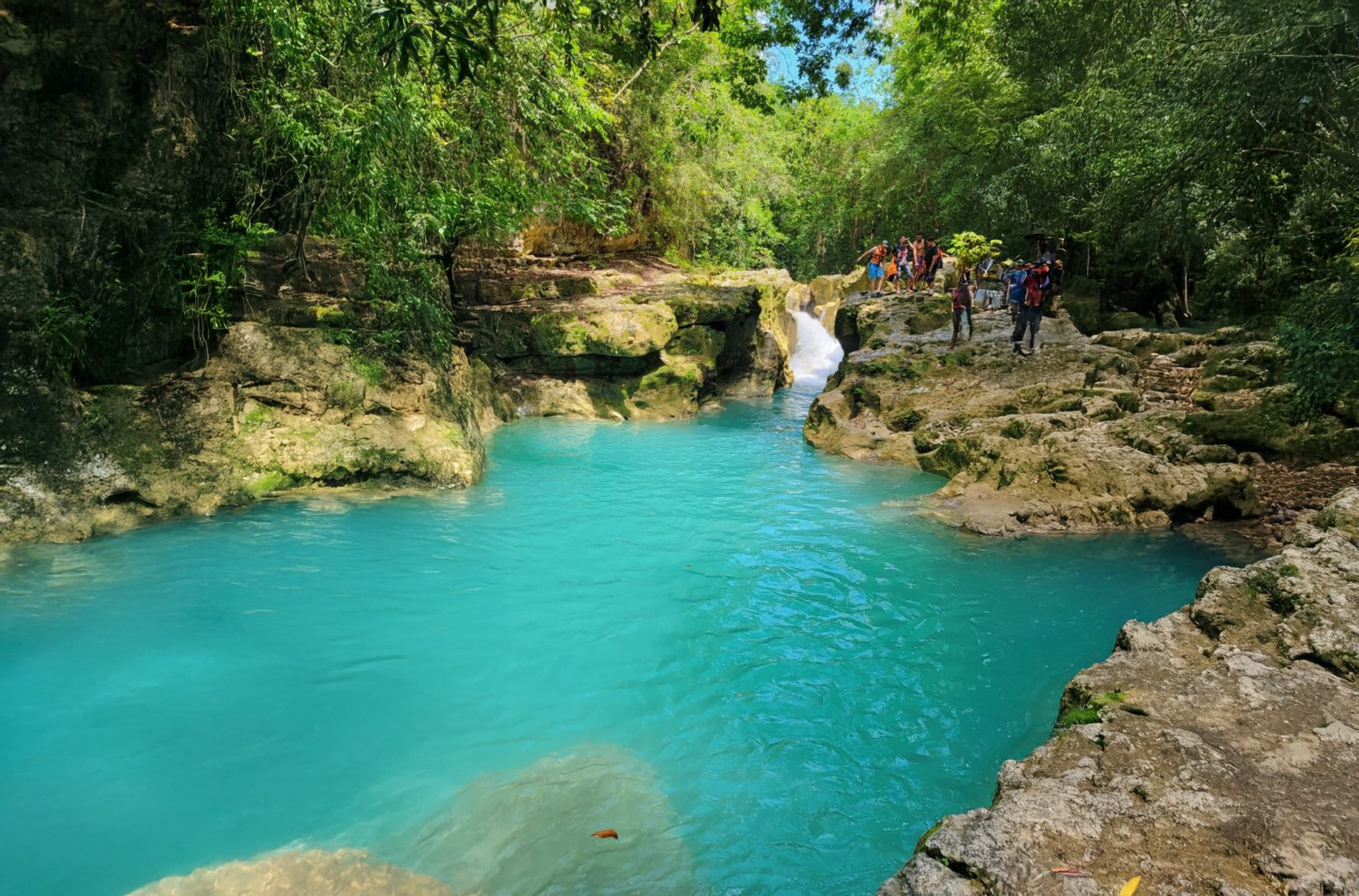 Hikers exploring Río Partido with turquoise waters and a small waterfall in the Dominican Republic