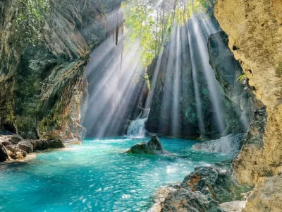 Sunlight streaming through jungle cliffs onto a hidden waterfall at Río Partido, Dominican Republic.