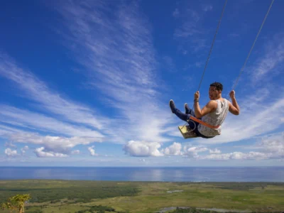 Man enjoying the giant swing at Montaña Redonda with panoramic ocean views in the Dominican Republic.