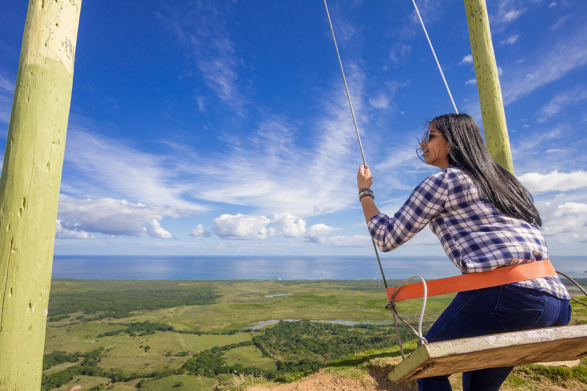 Woman sitting on the iconic swing at Montaña Redonda with ocean backdrop.